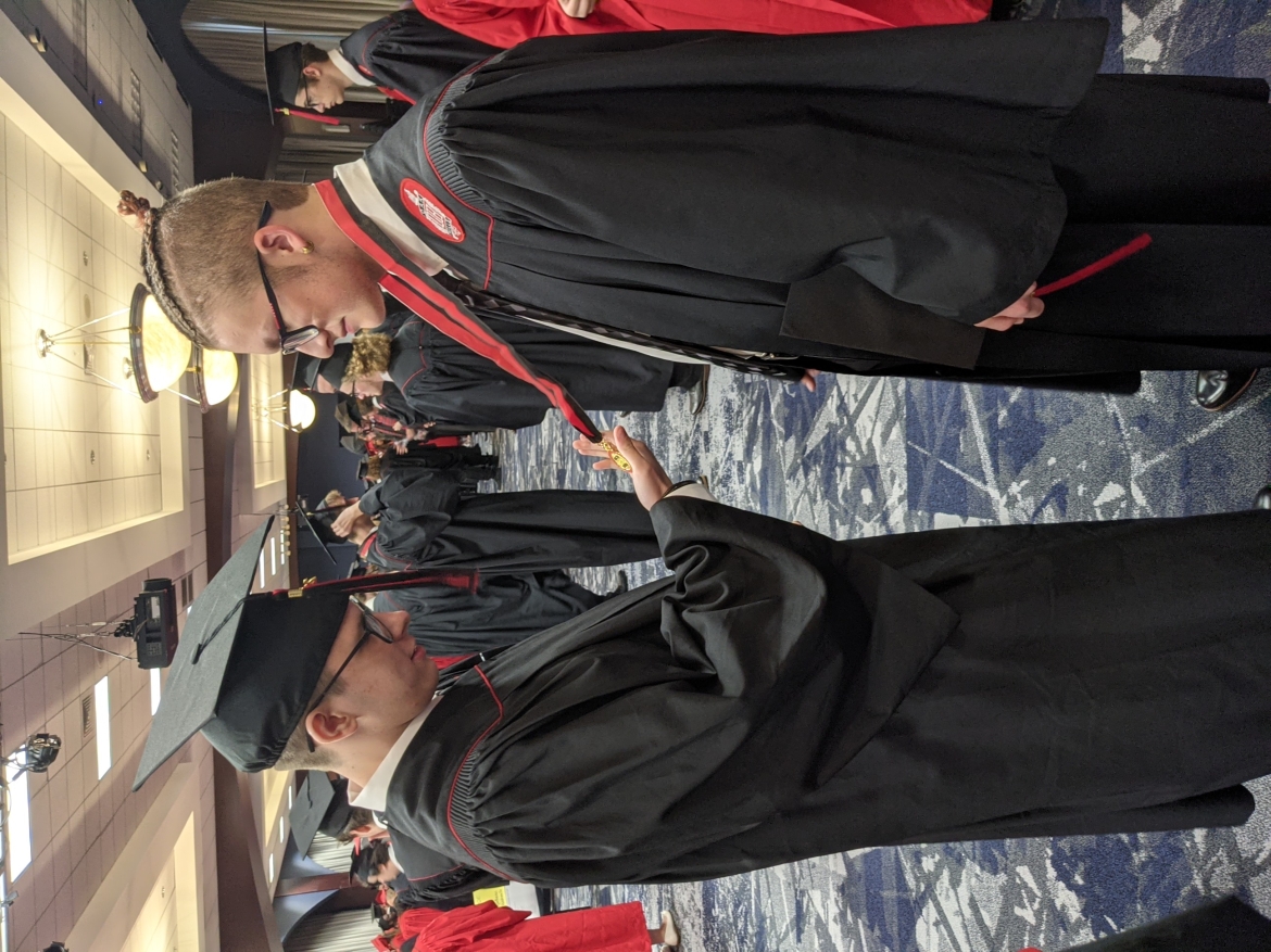 one graduate reading another graduate's medal